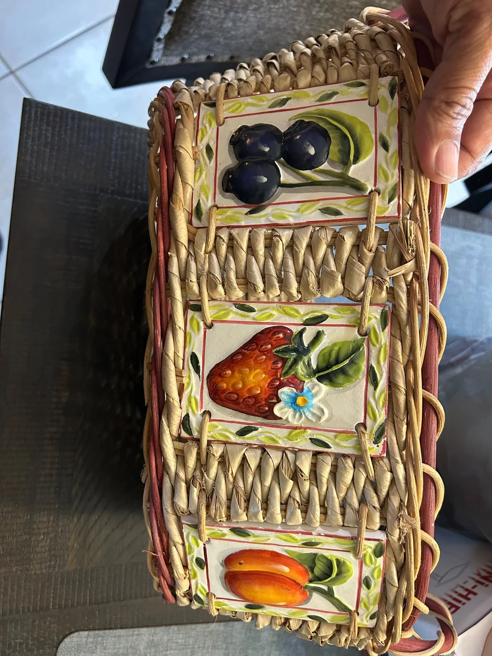 vintage woven wicker basket features hand-painted ceramic fruit tiles.